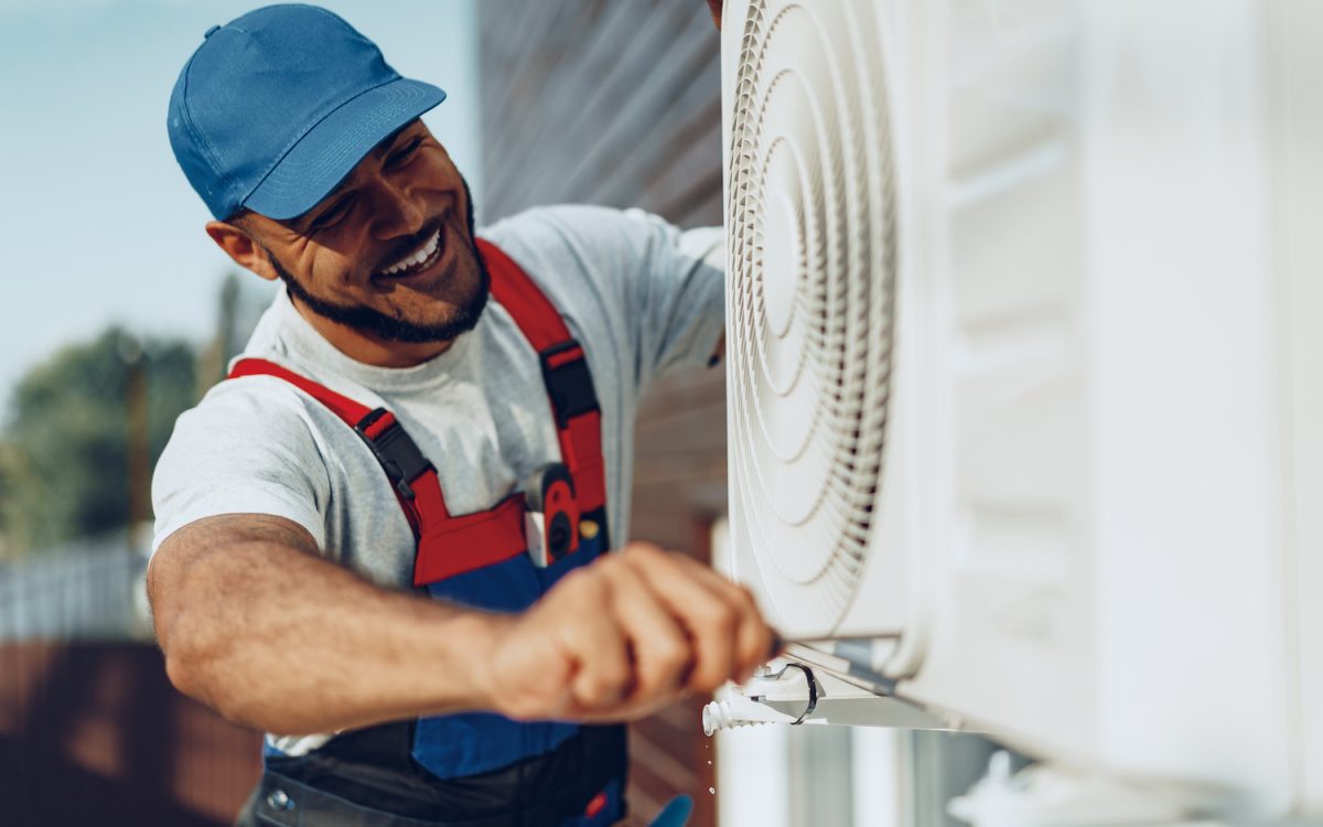 Young black man repairman checking an outside air conditioner unit close up