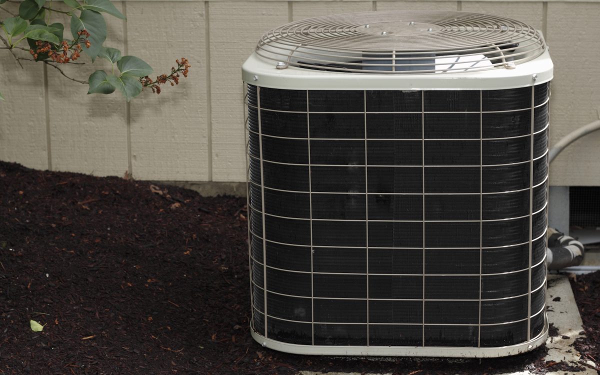 Free standing air conditioner in the exterior back of a home used to cool the house interior in the summer heat.