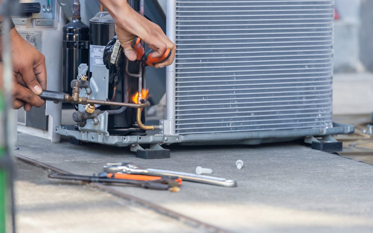 A person’s hands performing maintenance on an outdoor air conditioning unit in North Fort Myers.